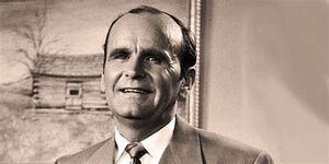 A middle aged man wearing a pinstripe suit with a tie